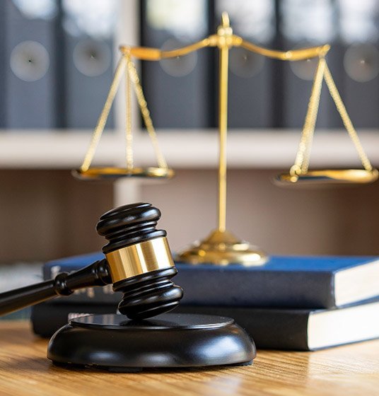 Balanza de la justicia junto a mazo de juez sobre escritorio.